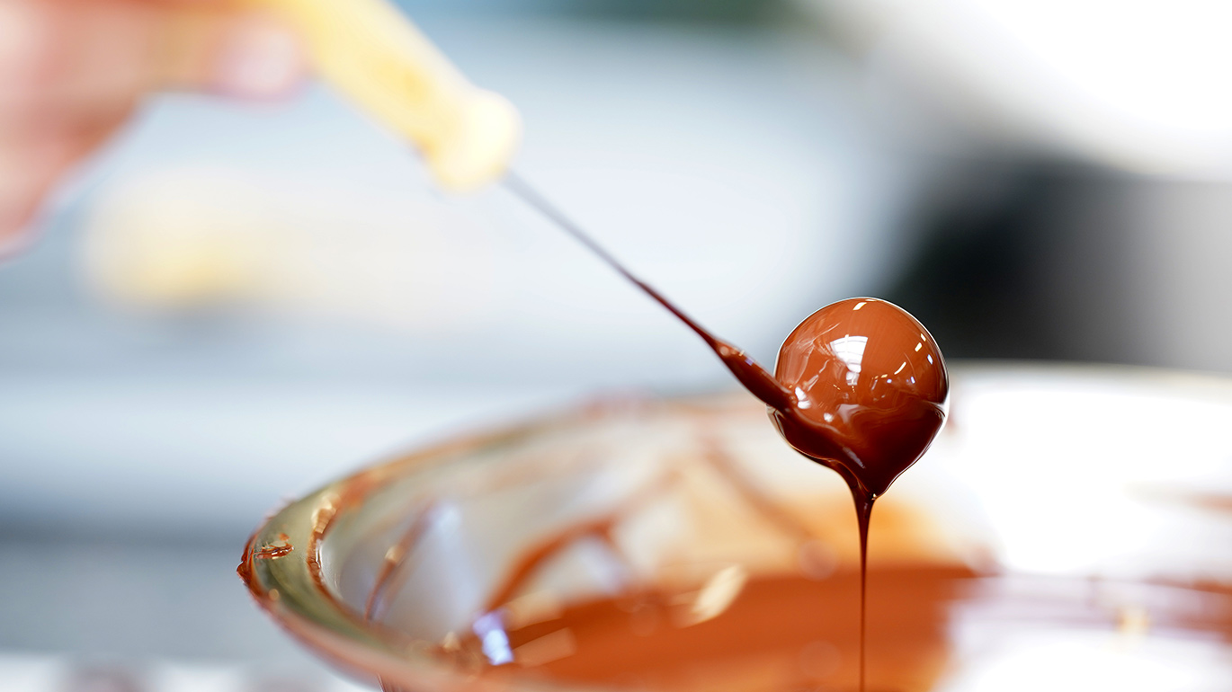 Praline wird in Schokolade getaucht